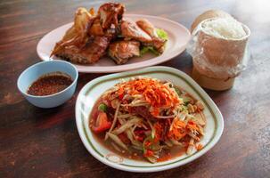 Thai papaya salad and grilled chicken on table photo