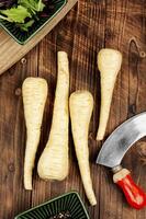 Raw parsnip roots on wooden table. photo