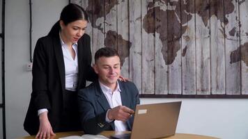 Company manager uses laptop, consults his secretary video