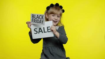 Cheerful blonde child girl showing Black Friday and Sale word advertisement inscriptions banners video