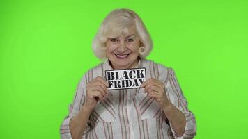 grande sconti per nonni. anziano nonna donna mostrando nero Venerdì iscrizione bandiera video