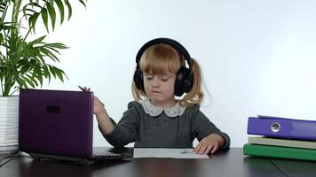 en línea aprendiendo, distancia educación, lección a hogar. niña haciendo colegio programa en línea en computadora video