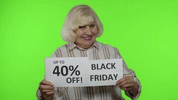 Sénior grand-mère montrant noir vendredi, 40 pour cent de remise publicité les inscriptions video