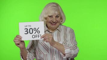 Senior grandmother showing Up To 30 percent Off inscription signs, rejoicing discounts. Black Friday video