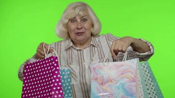 Grandmother holding shopping bags, rejoicing discounts in store, enjoying shopping with low prices video