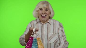 Senior grandmother raising shopping bags, celebrating, satisfied with purchase, discount. Chroma key video