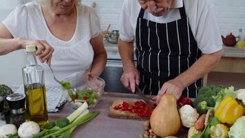 mayor vegano abuela y abuelo Cocinando ensalada con Fresco vegetales en cocina a hogar video