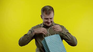 atraente homem mostrando Preto Sexta-feira inscrição a partir de compras bolsa, sorridente, alegria descontos video