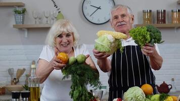 mayor abuelos Pareja en cocina. maduro hombre y mujer recomendando comiendo crudo vegetal comida video