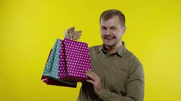 Joyful man showing Black Friday inscription from shopping bags, smiling satisfied with low prices video