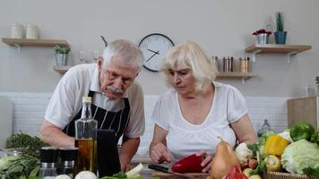 vegano mayor Pareja Cocinando ensalada con crudo vegetales. mirando en digital tableta para en línea receta video