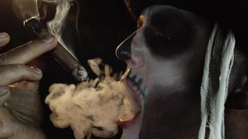 Scary guy in carnival costume of Halloween skeleton smoking cigar, making faces, showing tongue video