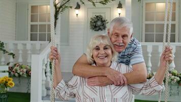 Senior couple together in front yard at home. Man swinging woman during Coronavirus quarantine video