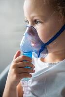 cerca arriba ver de pequeño niña son sentado y participación un nebulizador máscara propensión en contra el rostro, vías respiratorias tratamiento concepto foto