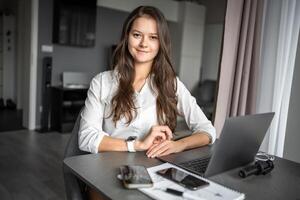 Portrait of smiling young business woman with laptop in home workplace, home office, home studying or teaching concept photo