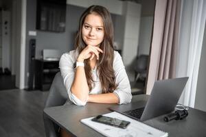 Portrait of smiling young business woman with laptop in home workplace, home office, home studying or teaching concept photo