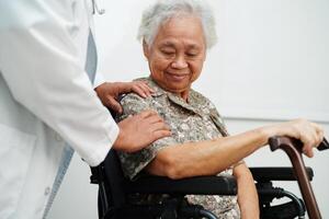 Doctor help Asian elderly woman disability patient sitting on wheelchair in hospital, medical concept. photo