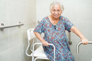 Asian elderly old woman patient use toilet support rail in bathroom, handrail safety grab bar, security in nursing hospital. photo