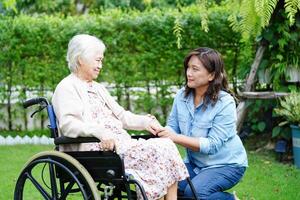 Caregiver help Asian elderly woman disability patient sitting on wheelchair in park, medical concept. photo