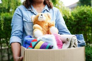 Volunteer collect cloth and doll in cardboard box to donate. photo