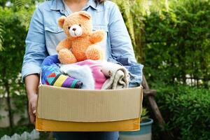 Volunteer collect cloth and doll in cardboard box to donate. photo