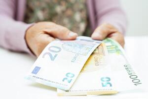 Retired elderly woman counting coins money and worry about monthly expenses and treatment fee payment. photo