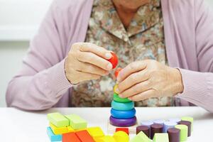 asiático mayor mujer jugando rompecabezas juego para tratamiento demencia prevención y Alzheimer enfermedad. foto