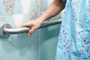 Asian elderly old woman patient use toilet support rail in bathroom, handrail safety grab bar, security in nursing hospital. photo