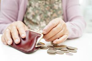 Retired elderly woman counting coins money and worry about monthly expenses and treatment fee payment. photo