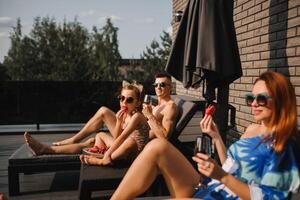 A happy family in swimsuits sunbathe in summer on their terrace on sun beds photo