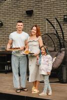 un contento familia tiene preparado almuerzo y será comer a su casa. retrato de un familia con comida en su manos foto