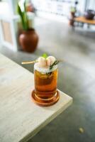 Fresh cold drink of lychee tea on a table with an elegant cafe in the background. photo