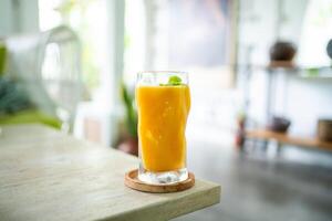 Fresh mango juice on table with luxury home blur background photo