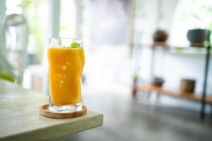 Fresh mango juice on table with luxury home blur background photo