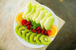 mixed fruit plate containing melon, strawberries, oranges and kiwi photo