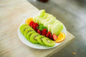 mezclado Fruta plato conteniendo melón, fresas, naranjas y kiwi foto