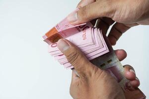 el proceso de contando indonesio rupia dinero en un blanco antecedentes foto