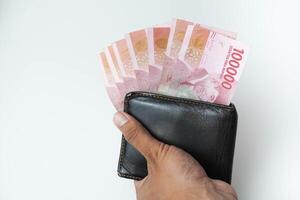 holding a wallet with indonesian money rupiah looking out of the wallet white background photo