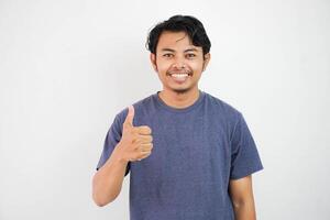 Young handsome asian man wearing casual with white background doing happy thumbs up gesture with hand. Approving expression looking at the camera showing success. photo