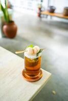 Fresh cold drink of lychee tea on a table with an elegant cafe in the background. photo