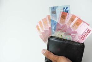 holding a wallet with indonesian money rupiah looking out of the wallet white background photo