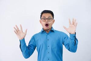 Surprised or Shock handsome Asian man with glasses in wearing blue shirt opening mouth and hands on isolated white background photo