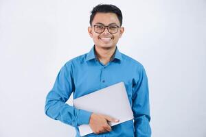 sonriente o contento asiático empresario con lentes participación ordenador portátil vistiendo azul camisa aislado en blanco antecedentes foto