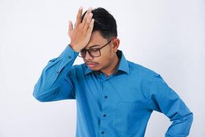 hermoso joven asiático empresario con lentes en vistiendo azul camisa olvidando algo, rápido frente con palma aislado en blanco antecedentes foto