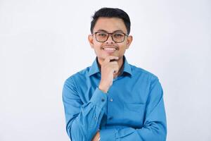 smiling employee asian man with glasses while holding the chin looking camera wearing blue shirt isolated on white background photo