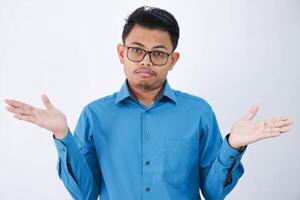 confuso hermoso joven asiático hombre con lentes en vistiendo camisa encogiéndose de hombros manos oblicuo y mirando decepcionado aislado en blanco antecedentes foto
