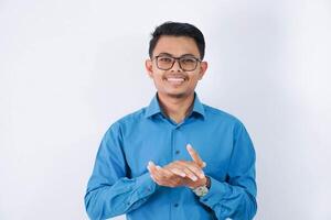 sonriente asiático empresario con lentes aplausos manos y mirando cámara vistiendo azul camisa aislado en blanco antecedentes foto