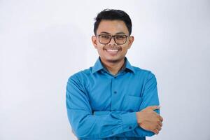 sonrisa o contento asiático empresario con lentes cruzado brazos y mirando cámara vistiendo azul camisa aislado en blanco antecedentes foto