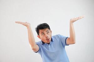 young asian man acting like he's holding up something heavy, but it's just empty copy space wearing blue t shirt isolated on white background. shocked face photo