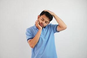 A portrait of young Asian man having has neck and shoulder pain wearing blue t shirt isolated on white background photo